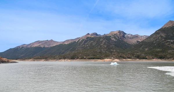 Landscape of Lago Argentino with mountains, blue sky and icy water.