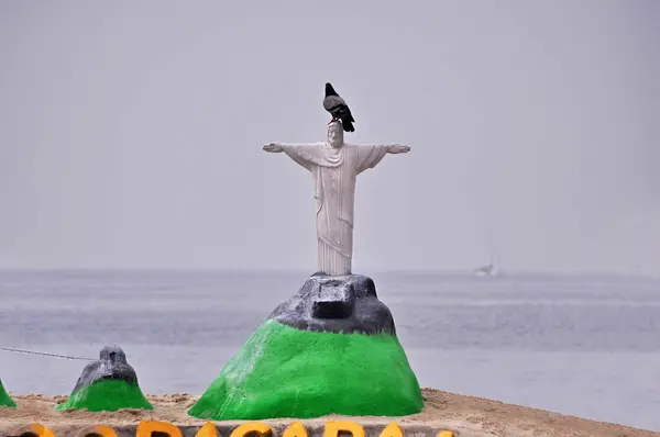 Handcrafted statue of Christ the Redeemer made from beach sand. With a pigeon on top of the sand statue. Problem concept in Rio de Janeiro.