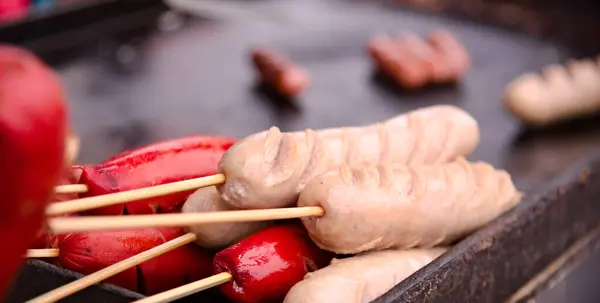 Traditional German Bavarian white sausage with other red sausages frying on the hot plate