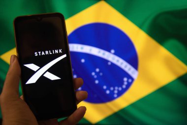 Elinde Starlink şirketinin logosu ve arka planında Brezilya bayrağı olan bir cep telefonu var. Görüntü, Elon Musk 'ın Brezilya Yüksek Mahkemesi ile olan sorununa atıfta bulunuyor. Rio de Janeiro / Brezilya - 08.30. 2024