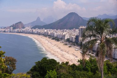 Copacabana beach with sand, sea and shore in the foreground and mountains and blue sky in the background. Aerial view. clipart