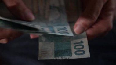 Brezilya 'nın gerçek para sayımı. 100 reais. İş konsepti, ekonomi, yolsuzluk, Brezilya 'daki borçlar. Para aklamadan elde edilen parayı sayan birinin yakın çekimi. Brezilya 'da para aklama. Gerçek banknotlar kurumaya bırakıldı.. 