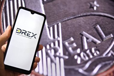 Brezilya 'nın dijital para birimi olan Dijital Real X (Drex) logosu, arka planda Brezilya para birimi bulunan bir akıllı telefon ekranında sergilenmektedir. Brezilya para birimi Drex. Rio de Janeiro, Brezilya - 01.05.2025