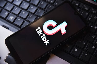 Bilgisayar klavyesinin üstünde TIKTOK uygulama logosu olan akıllı telefon. Teknoloji, sosyal medya ve dijital eğlence anlayışı. Tiktok uygulamalı cep telefonu. Rio de Janeiro, Brezilya - 01.16.2025.