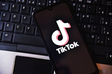 Bilgisayar klavyesinin üstünde TIKTOK uygulama logosu olan akıllı telefon. Teknoloji, sosyal medya ve dijital eğlence anlayışı. Tiktok uygulamalı cep telefonu. Rio de Janeiro, Brezilya - 01.16.2025.
