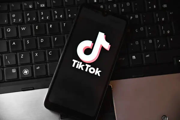 Bilgisayar klavyesinin üstünde TIKTOK uygulama logosu olan akıllı telefon. Teknoloji, sosyal medya ve dijital eğlence anlayışı. Tiktok uygulamalı cep telefonu. Rio de Janeiro, Brezilya - 01.16.2025.