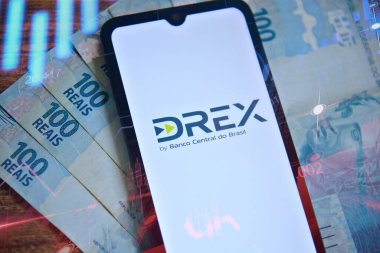 Rio de Janeiro, Brezilya - 01.27.2024: Akıllı telefon ekranında Dijital Real X (Drex) logosu ve borsa grafikleri. Arka planda 100 reais banknot var. Yeni Brezilya dijital para birimi. DREX.