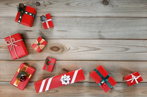 Red boxes with various decorations. Top view. Present for New Year. Copyspace. Many boxes with gifts in red wrapping paper are decorated with Christmas decor on wooden background. Flatlay. Space for text.