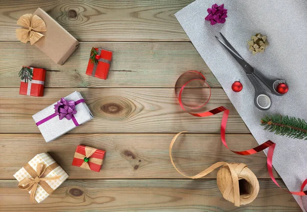 Hediye dekorasyonu. El işi hediye paketi kavramı. Flatlay. Tahta masadaki hediye kutularını süslemek için malzemeler. Üst Manzara. Noel süsü için çeşitli fikirler. Tasarım için mallar