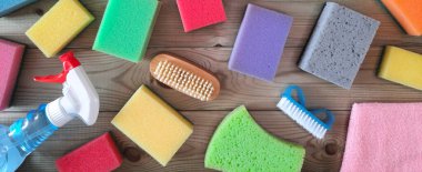 Bardak için sıvı, mendil, bulaşık yıkamak için mutfak süngeri. Flatlay. Uzun başlık afişi. Ev temizlik aksesuarları ahşap masada yatar. Üst Manzara. Temizleme şirketi başlık şablonu