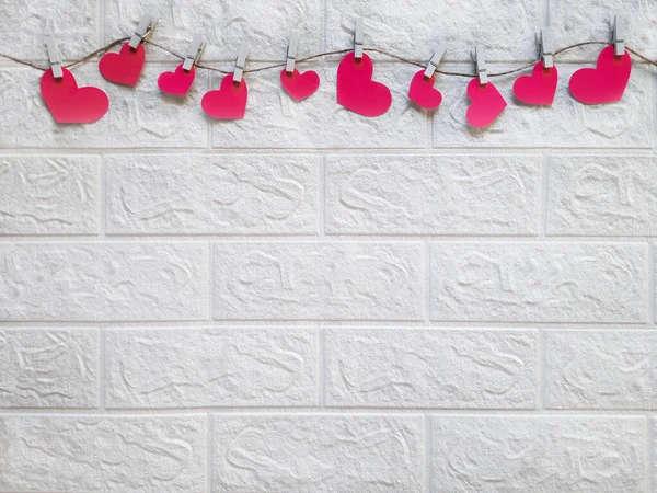Brick wall decorated with hearts on rope for hen party. Space for text. Team Bride. Theme of organizing and holding bachelorette party. Copy space. Valentines on clothespins. Flat lay.