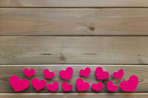 Valentines on table. Flatlay. Pink heart shaped confetti lies from below on wooden background. Space for text. Mockup for advertisement romance valentine's day, date, engagement. Top view. Copy space.