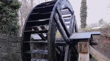 Slow motion of water mill wheel with falling drops. Vintage technology research concept. Travel and excursions to historical places. Past is in present. History of industry, hydropower.