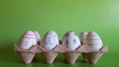Paskalya avı için dekoratif yumurta hazırlığı. Geleneksel dekorasyon, ev dekorasyonu, çocuklar için el işi. Süslü yumurtalı tepsiden kadının eli bir yumurta alıyor. Tatil hazırlama kavramı