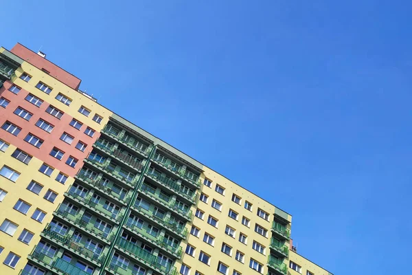 Multi-family high-rise building with multicolored facade on background of blue sky diagonally. Bottom view. Apartment building in Europe. concept of construction, reconstruction, insulation of housing.
