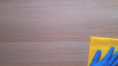 Evi temizliyorum. Temizlik ve yıkama zamanı konsepti. Sarı bez mendilli, mavi koruyucu lastik eldiven ahşap masa. Toprak ve tozun kaldırılması. Günlük ev işleri.