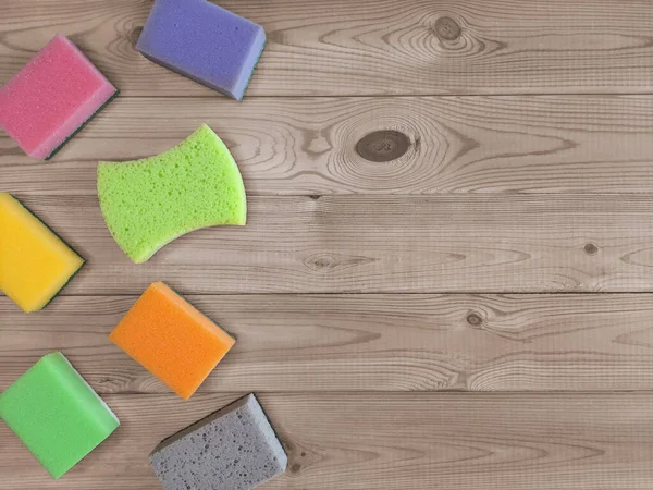 Cleaning sponges for different purposes. Flat lay. Concept of cleanliness in kitchen. Place for text.  Kitchen sponges of different shapes and colors on left on wooden background. Copy space. Top view.