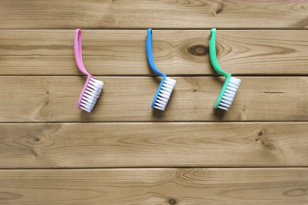 Plastic cleaning brushes for dishwashing. Copy space. Top view. Three colored scrubber for kitchen on wooden background. Flat lay. Place for text. Concept of quality cleaning services.