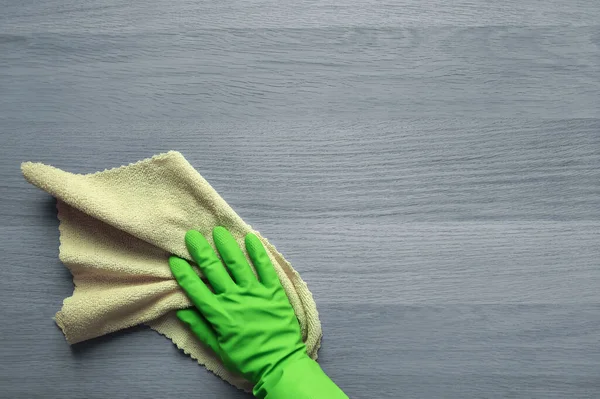 stock image Kitchen Duty. Copy space. Top view. Concept of daily cleaning, washing, housework. Green rubber-gloved hand tackles grey wooden table with microfiber cloth. Flat lay. Place for text.