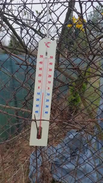 天気予報 垂直ビデオ 暖かく待ってる 古い温度計はメッシュフェンスにかかっています 曇りの春または秋の日 — ストック動画