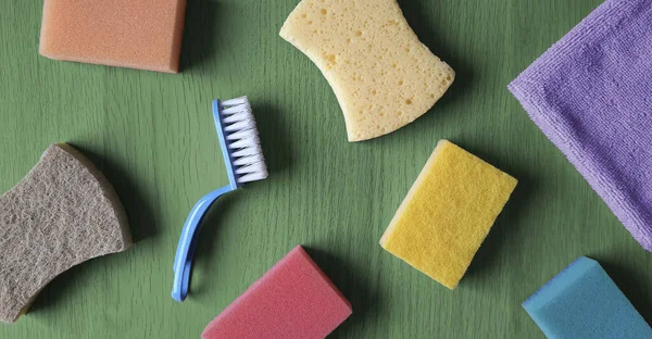 Cleaning products banner. Flat lay.  Kitchen sponges, dishcloth, scrub brush on wooden table background. Top view. Home cleaning service concept. Header for website, blog, article, advertisement