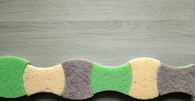 Ahşap arka planda mutfak süngeri olan pankart. Bulaşıkları dalgalı sıra şeklinde yıkamak için. Düz yatıyordu. Uzayı kopyala Hırdavatçı ve temizlik servisi. Web sitesi, blog, broşür başlığı.