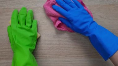 Takım çalışması. Mutfakta temizlik süreci. Deep Clean House in One Day konsepti. Lastik koruyucu eldivenli iki kişi masaları bez ve mutfak süngeriyle siliyor. Çocuk ve yetişkinin eli..