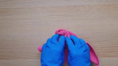 Mutfakta temizlik süreci. Deep Clean House in One Day konsepti. Pembe bulaşık bezli mavi lastik eldivenli iki el dikkatlice ahşap masayı siler. Zorlu topraklarla savaşmak
