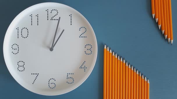 1点钟方向白天 学习时间 回学校去用铅笔在蓝色的桌子背景上用白色的钟面看着 午饭时间时间过去了网上学习的概念 截止日期 时间表 午休时间 — 图库视频影像