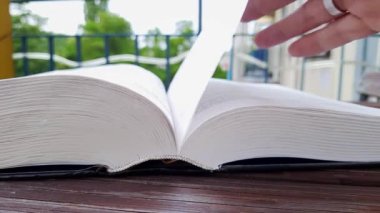 Kadınlar el çabukluğuyla kitaba göz atarlar. Arka planda şehir siluetinin bulanıklaştığı balkonda kitap okumak. Kitap severler günü. Kitapla sıcak bir hafta sonu. Modern ve klasik edebiyat. Yaşam biçimi.