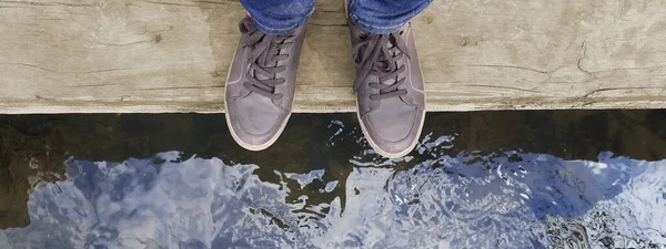 Kahverengi ayakkabılı bir adam ya da bir kadın suyun üzerinde tahta bir kütüğün üzerinde duruyor. Yaşam dengesi kavramı, yaşam tarzı. Web sitesi için başlık, günlük