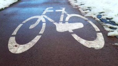Bisiklet yolu ve kar. Bisiklet yolunda yol işaretleri var. Kış sporları, karlı şehirde aktif eğlence. Başlangıç, bisiklet sezonunun açılışı