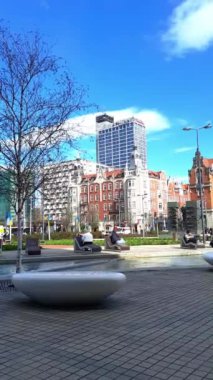 Şehir merkezindeki dinlenme alanı. Modern ve tarihi binaların arka planında, iş bölgesinde su kanalı yakınında rahat banklar. Dikey video. 27-03-2024 Katowice, Polonya, Avrupa.