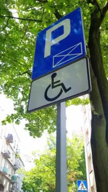 Sadece engelli sürücüler için park yeri. Ağaçların arka planına karşı yol işareti. Erişilebilir park yeri kavramı. Engelli insanlar için uyarlanmış alanlar. Katılım. Dikey video.