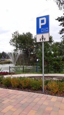Ebeveyn ve çocuk parkı tabelası. Çeşmeli, çiçekli, ağaçlı, yaya yollu, rahat bir park alanında aile park yeri. Çocukları olan tüm aile için rahat bir seyahat ve rahatlama..