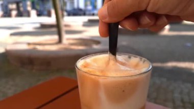 Kişi kaşık kullanarak sütlü köpüğün kalitesini kontrol eder. Kahve ve kahve yapma sanatı, baristalık mesleği. Sıcak bir kafede nefis bir kahvenin tadını çıkarıyorum..