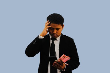 Yetişkin Asyalı adam Endonezya 'da kağıt para tutarken düşünce hareketi yapıyor.