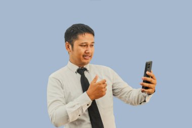 Adult man asian with flat expression  and give thumb to mobile phone clipart