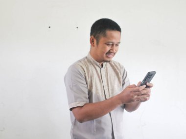 Yetişkin Asyalı adam gülümsüyor ve cep telefonuna bakıyor