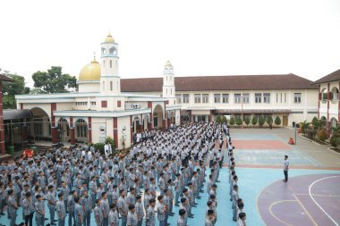 Subang, Indonesia - May 2024: Middle school, high school students and teachers taking part in a ceremony to commemorate National Education Day on the school field clipart