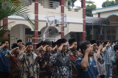 Subang, Endonezya - Mayıs 2024: Öğretmenler okul alanındaki Milli Eğitim Günü münasebetiyle düzenlenen etkinlikler sırasında bayrağa karşı saygılı bir konumda bulunuyorlar