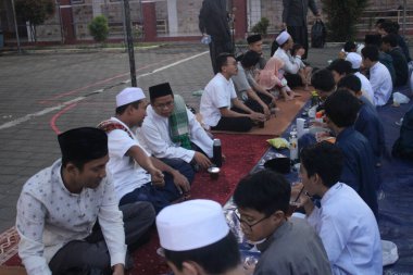 Ortaokul öğrencileri, 29 Mart 2024 'te Endonezya' nın okul ve cami bölgesinde birlikte kahvaltı etmeden önce bir konferans dinliyorlar.