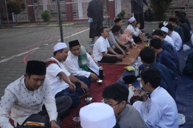 Ortaokul öğrencileri, 29 Mart 2024 'te Endonezya' nın okul ve cami bölgesinde birlikte kahvaltı etmeden önce bir konferans dinliyorlar.