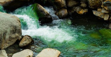 Kaplıcaya yakın bir yerde, su parlak yeşil ve hızlı akıyor gibi görünüyor..