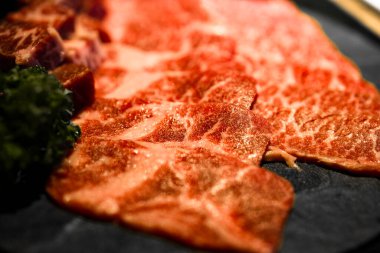meticulously cut and well-arranged beef with premium marbling alongside fresh green herbs clipart
