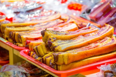 an array of traditional cured bacon with a golden hue and rich fat marbling at a market stall clipart