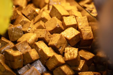 Yiyecek tezgahında haşlanmış tofu derisi yığını. Bu tofu derileri düzgünce bir araya toplanmış, dokularını ve renklerini renklendiriyorlar..