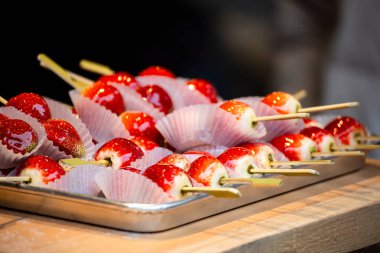 Bir demet parlak kırmızı çilekli elma elması bir tepside düzgünce düzenlenir.