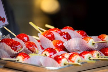 Bir demet parlak kırmızı çilekli elma elması bir tepside düzgünce düzenlenir.