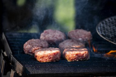 Kömür ızgarasında birkaç kalın hamburger köftesi cızırdıyor.
